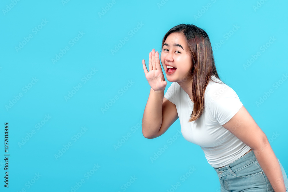 Smiling young woman whispers a secret or shares gossip, cupping her hand to her mouth against a bright blue background. Smiling young woman whispers a secret or shares gossip, cupping her hand to her mouth against a bright blue background.
