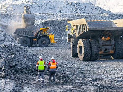 Open pit coal mining with two male workers in high visibility gear, aerial top view