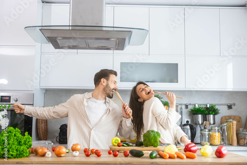 A vibrant kitchen scene depicts a couple joyfully cooking and enjoying each other's company amidst fresh ingredients.