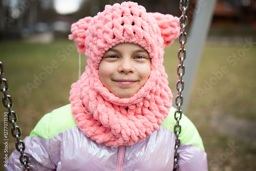 Obraz na płótnie Little funny girl in funny pink hat swinging on swing in park outdoors w salonie