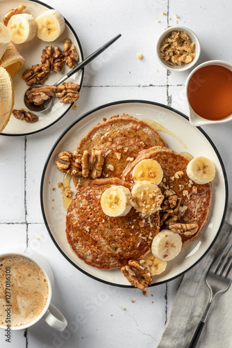 Healthy oatmeal pancakes with banana, nuts and honey on white tile background. Morning breakfast, top view. Pancake day or Maslenitsa recipe