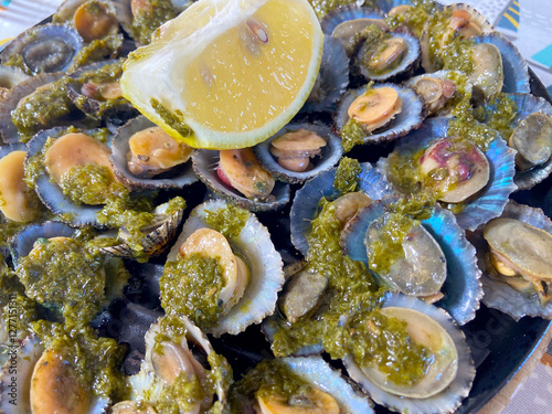 Grilled limpets Lapas grelhadas served with lemon close up. Traditional dish of Portugal and a typical snack of the Canary Islands.Seafood concept.
Selective focus. photo