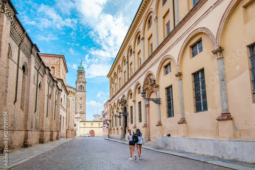Three young women tourists walking in Piazza Duomo in Parma, near the Duomo and Baptistery, enjoying a sunny summer day while admiring the ancient architecture