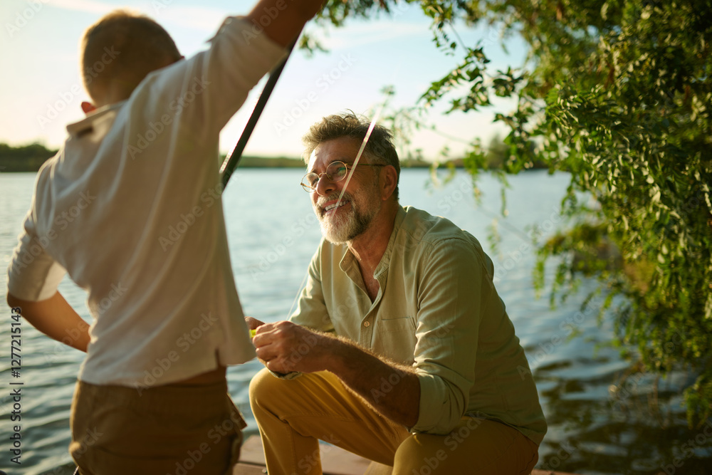 Grandfather helping grandson preparing fishing rod on pier Grandfather helping grandson preparing fishing rod on pier