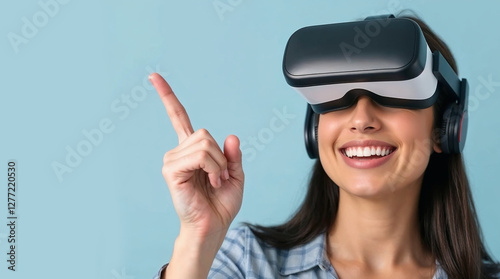 woman in virtual reality glasses pointing at smth and smiling, light blue background photo