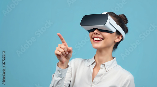 woman in virtual reality glasses pointing at smth and smiling, light blue background photo