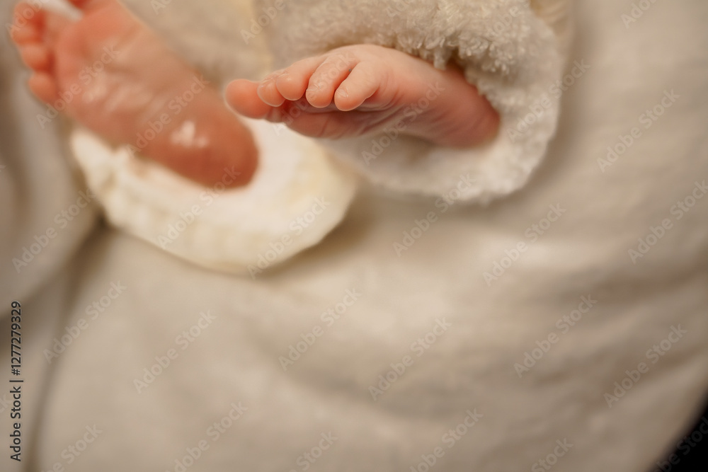 Fototapeta premium Tender Close-Up of a Baby's Feet in a Soft White Outfit
