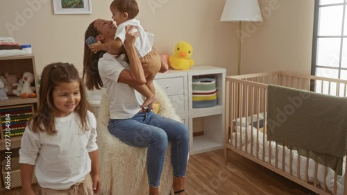 Woman plays with son and daughter in cozy bedroom with crib, showing love and happiness in a family home setting, highlighting a nurturing environment.
