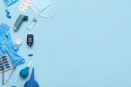 Composition with pulse oximeter, inhaler, syringe and medicines on blue background photo