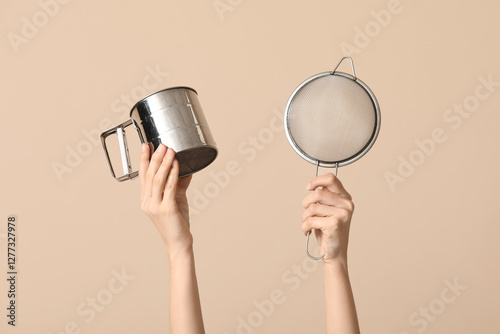 Female hands with sieves on beige background photo