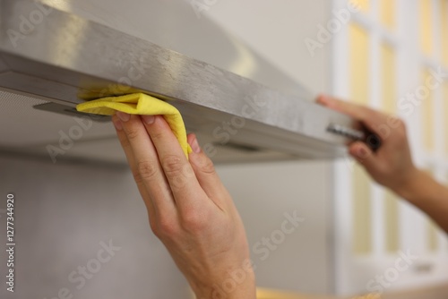 Man cleaning kitchen hood with rag indoors, closeup