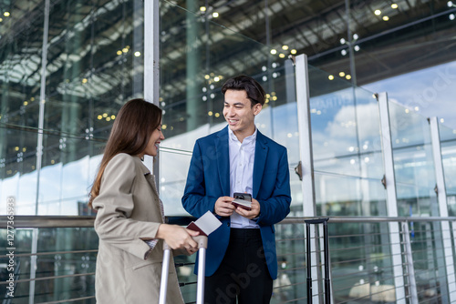 Young businessman and woman standing outdoors of airport terminal.