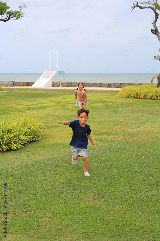 Φωτογραφία Asian little boy and young girl child running outdoors in garden near coast