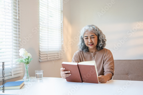 Beautiful mature woman reading book, feeling cozy and happy. Weekend activity for older woman, relaxing at home.. photo