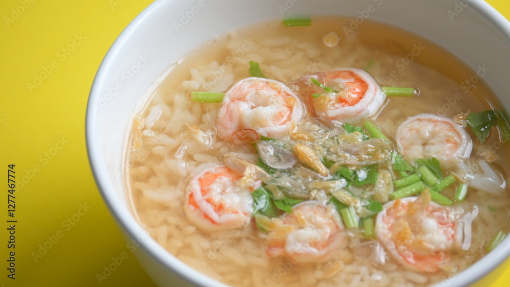 rice soup with shrimp in white bowl on yellow background