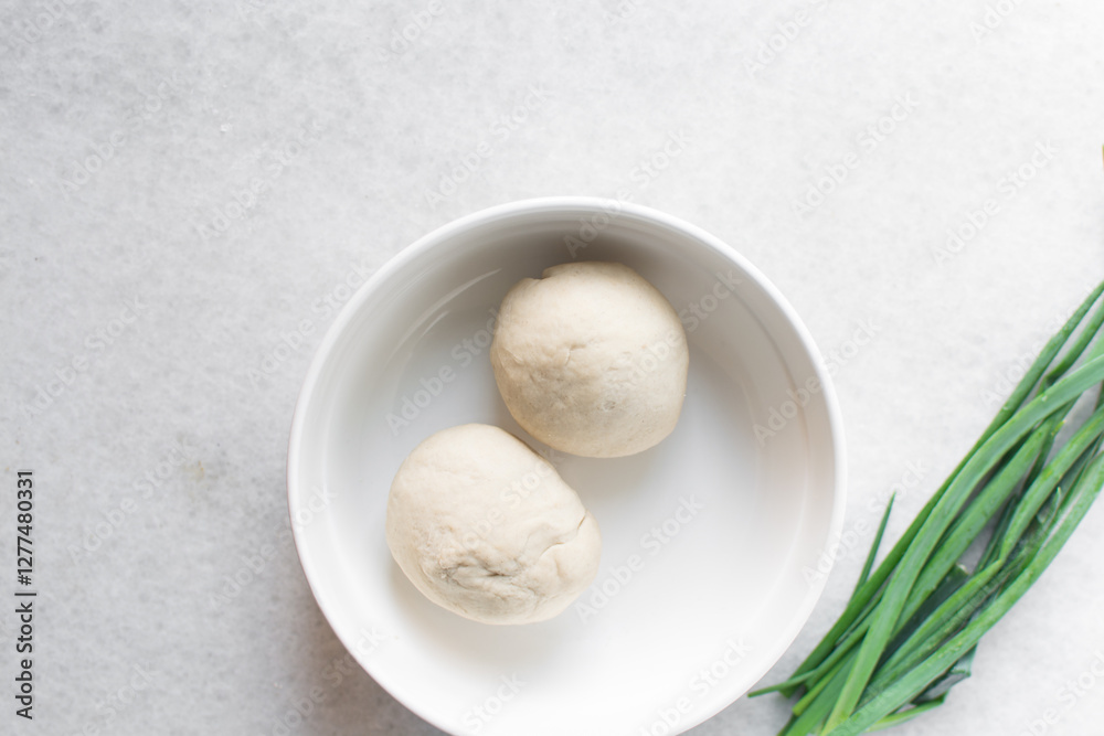 Fototapeta premium Overhead view of chinese scallion pancake dough on white countertop, top view of homemade scallion pancake dough, process of making cong you bing