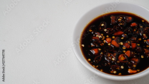 Sweet soy sauce chili sauce with sliced ​​red cayenne pepper served on a white plate placed on a white base and background (isolated white).