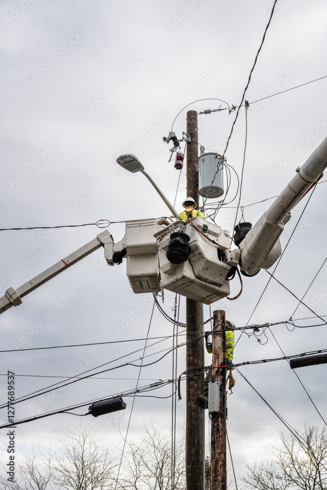 Line crew workman in hydraulic lift bucket, and lineman is climbing gear on wood pole, high up working on utility power lines, residential power line maintenance and upgrade, install new transformer a Line crew workman in hydraulic lift bucket, and lineman is climbing gear on wood pole, high up working on utility power lines, residential power line maintenance and upgrade, install new transformer a