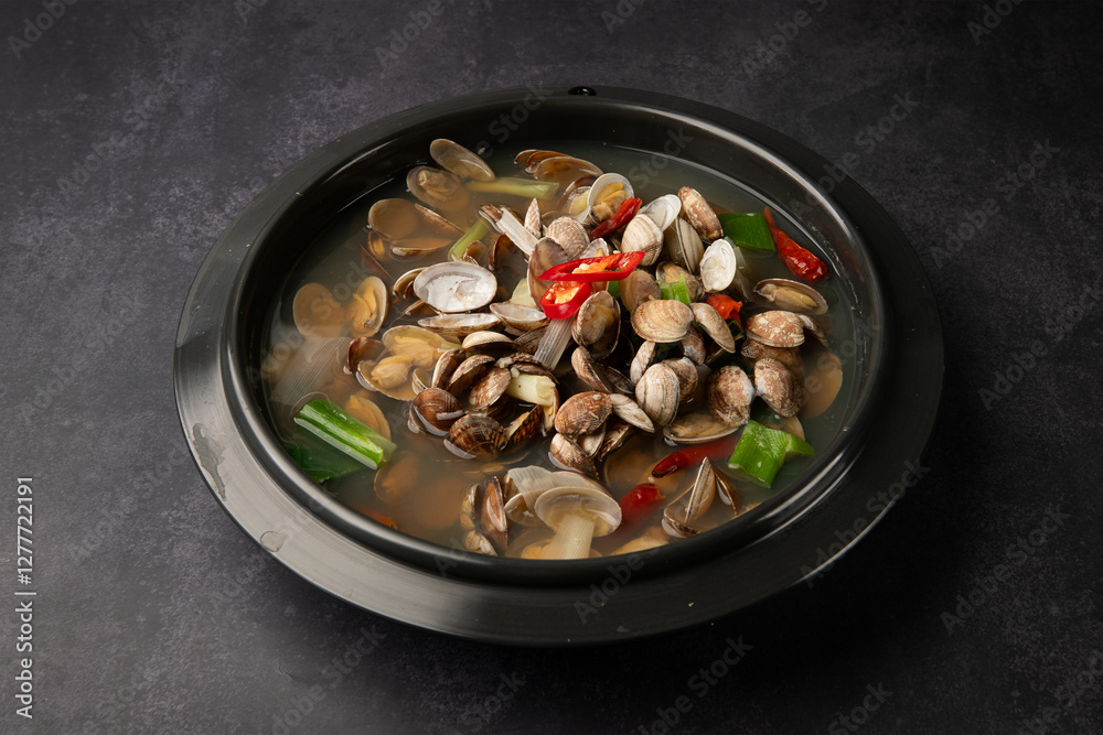 Seafood soup with clams, mussels and chili peppers in bowl on dark background, top view Seafood soup with clams, mussels and chili peppers in bowl on dark background, top view