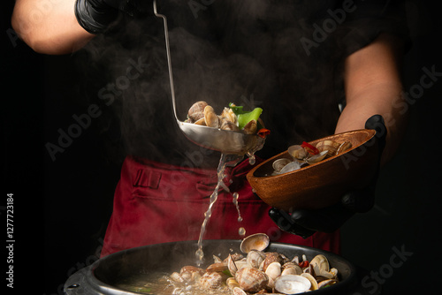 Chef cooking clams in pan on black background, closeup