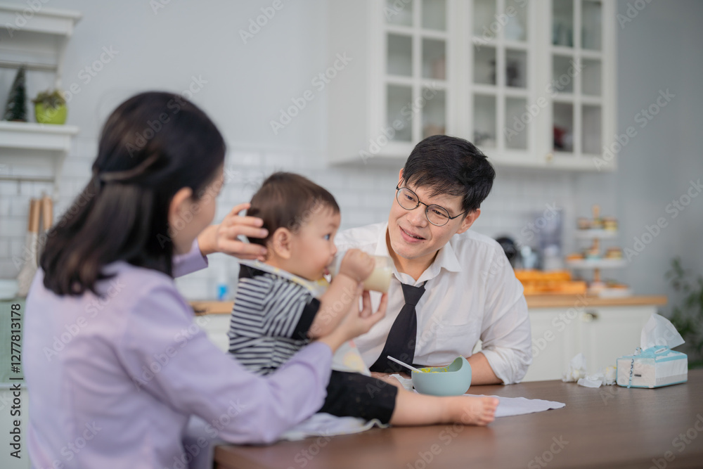 Caregiver feeding toddler in a bright kitchen setting with mother assisting during a mealtime Caregiver feeding toddler in a bright kitchen setting with mother assisting during a mealtime
