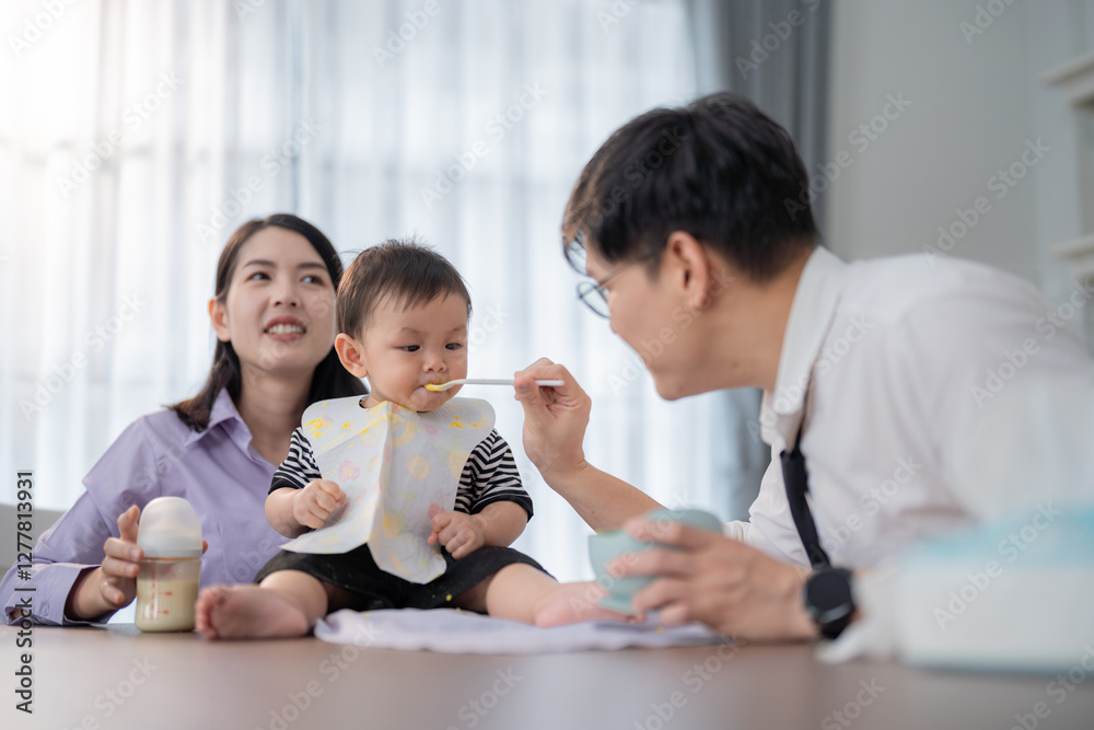 Parents feeding their toddler during a joyful mealtime at home in a stylish, modern kitchen Parents feeding their toddler during a joyful mealtime at home in a stylish, modern kitchen