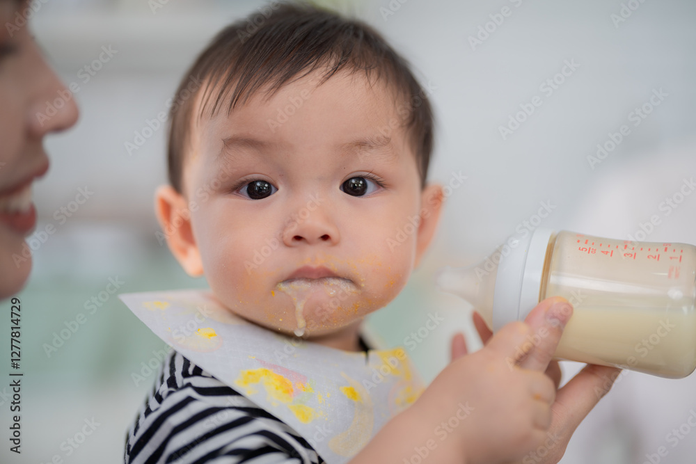 Baby enjoying a bottle while wearing a bib, surrounded by a caring adult in a bright, cozy setting Baby enjoying a bottle while wearing a bib, surrounded by a caring adult in a bright, cozy setting