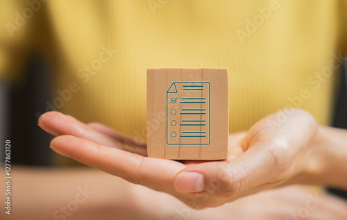Hand holding wooden block and filling survey form online.