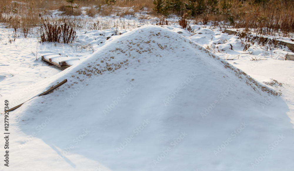 A large mound of snow sits in the middle of a field