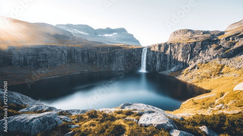 Waterfall cascades into a pristine lake surrounded by rocky mountains