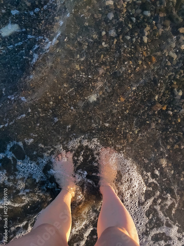 women's legs on the beach in an incoming wave top view