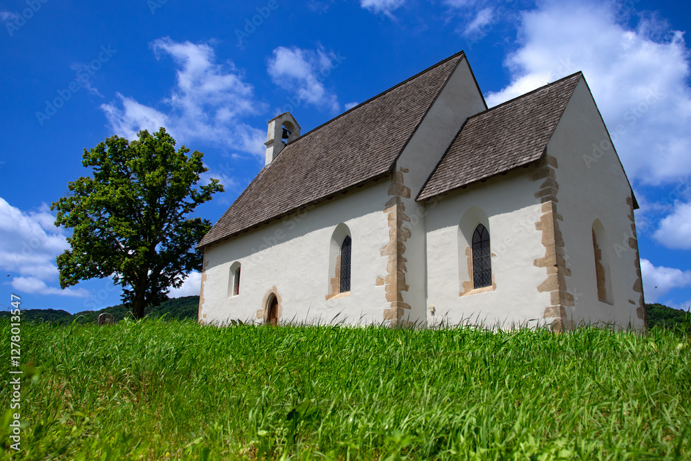 Fototapeta premium The Church of St. Andrew in Kamešnica, dating back to the 14th century, has preserved its original Gothic appearance with a steep double-pitched roof.