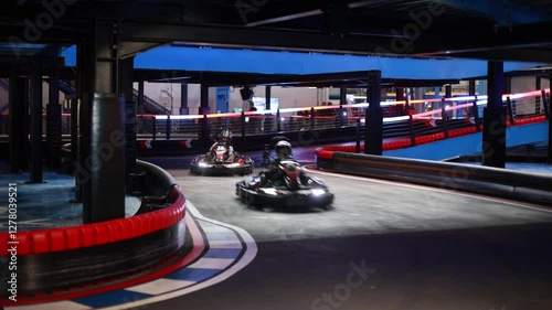 Child, driving go cart car in an indoor race track, enjoying sport racing