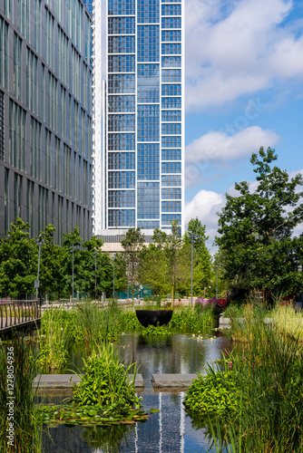 Lush urban pond surrounded by contemporary buildings in London, showcasing green infrastructure and sustainable city planning.