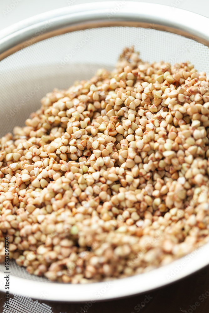 Buckwheat Groats in Strainer - Close-up of toasted buckwheat seeds ready for cooking, showing texture, color and preparation stage Buckwheat Groats in Strainer - Close-up of toasted buckwheat seeds ready for cooking, showing texture, color and preparation stage