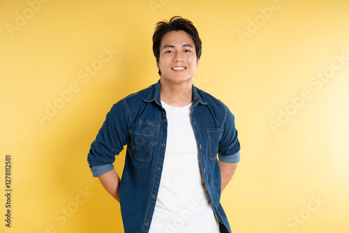 Portrait of handsome Asian man posing on yellow background