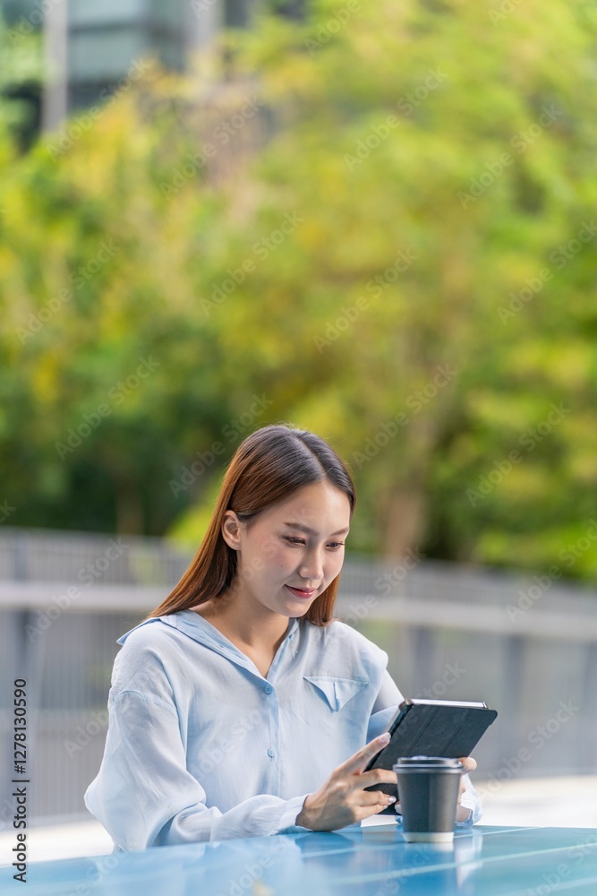Young Asian Woman Using Tablet and Having a Coffee Outdoors a Business District Young Asian Woman Using Tablet and Having a Coffee Outdoors a Business District