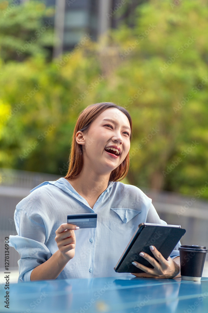 Fototapeta premium Asian Woman Using Tablet and Credit Card Outdoors a Modern Greenery Office Building