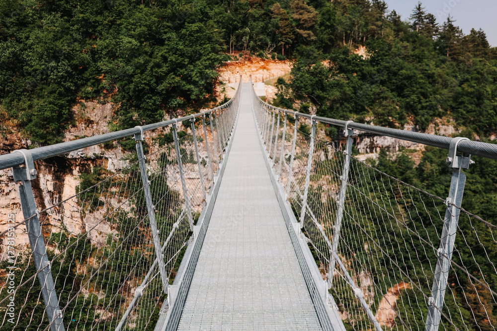 Obraz premium Suspension bridge between mountains. The picture is taken from the bridge and shows the opposite direction.