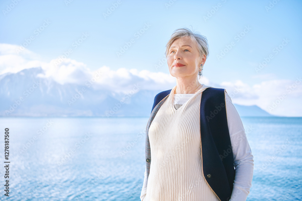 Fototapeta premium Outdoor portrait of beautiful 55 - 60 year old woman enjoying nice sunny day by the lakeside, image taken in Montreux, Switzerland