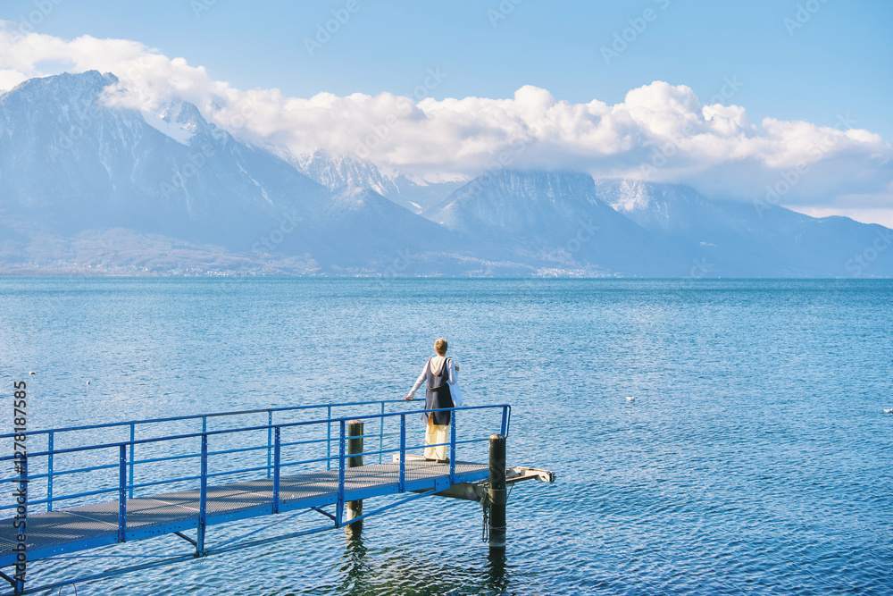 Naklejka premium Nature background of lake Geneva and swiss Alps, woman admiring winter landscape, image taken in Montreux, Switzerland