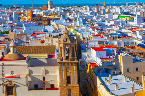 Obraz na płótnie Aerial view of city of Cadiz, Spain, dense array of white buildings with flat roofs and prominent church tower in foreground. Vibrant colors of the rooftops and the visible coastline highlight Cadiz w salonie