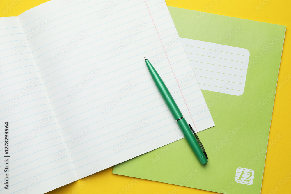 Copybooks and pen on yellow background, top view Copybooks and pen on yellow background, top view
