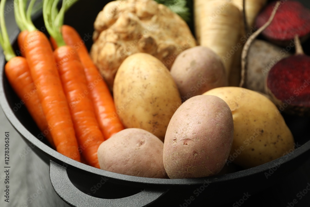 Different root vegetables in pot on black table, closeup Different root vegetables in pot on black table, closeup