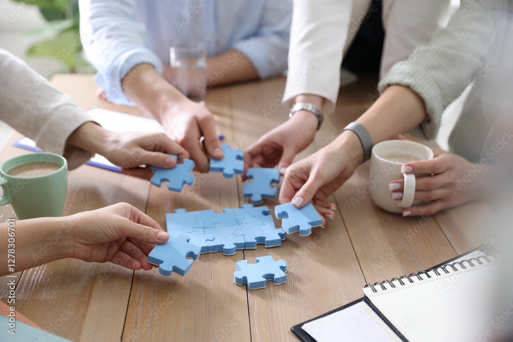 Unity concept. People putting puzzle pieces together at wooden table indoors, closeup Unity concept. People putting puzzle pieces together at wooden table indoors, closeup