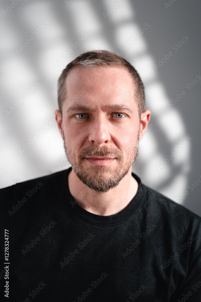 Intensives Porträt eines Mannes mit Bart und schwarzem Shirt im Schattenspiel Intensives Porträt eines Mannes mit Bart und schwarzem Shirt im Schattenspiel