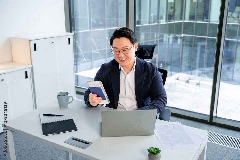 Professional businessman in formal attire reading a document at his desk in a modern office, showcasing a productive and positive atmosphere. The workspace contains a laptop, stationery. Professional businessman in formal attire reading a document at his desk in a modern office, showcasing a productive and positive atmosphere. The workspace contains a laptop, stationery.