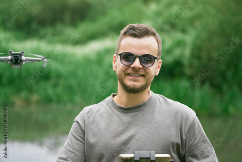 Smiling man in sunglasses piloting drone in nature setting photo