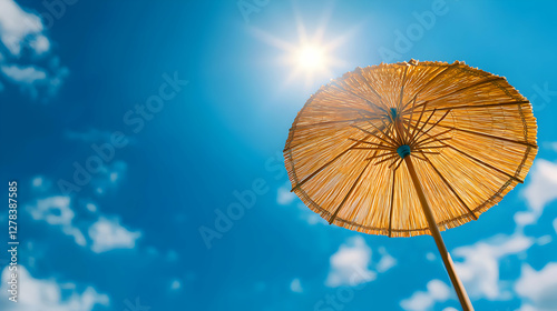 Woven Beach Umbrella Against a Bright Blue Sunny Sky with Scattered Clouds