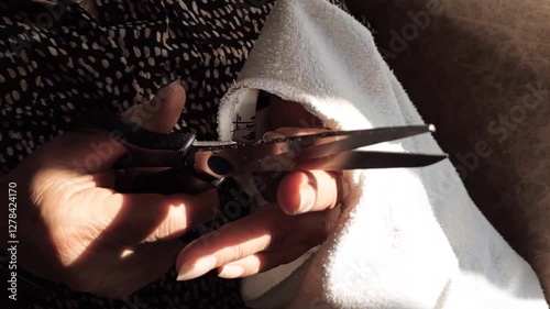 A person makes the final cut to remove the sleeves of a hoddie. Cutting a garment